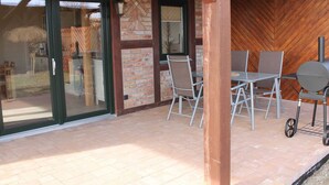 Un patio al aire libre con pared de ladrillo, techo de madera y una estación de parilla.