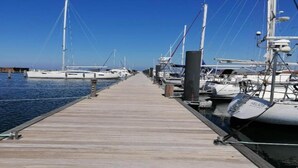 Un muelle de madera que conduce a un puerto deportivo con varios yates amarrados.