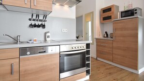 Eine moderne Küche mit Holzschränken, Edelstahlgeräten und einem eingebauten Ofen.