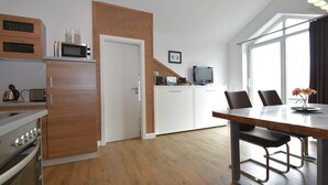 Eine moderne Küche mit Holzschränken, einer Mikrowelle und einem Essbereich mit Tisch und Stühlen.