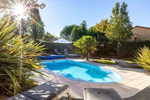 A swimming pool with lounge chairs, surrounded by greenery and a clear sky. - Villa in France With Private Heated Pool (Les Sables-d'Olonne)