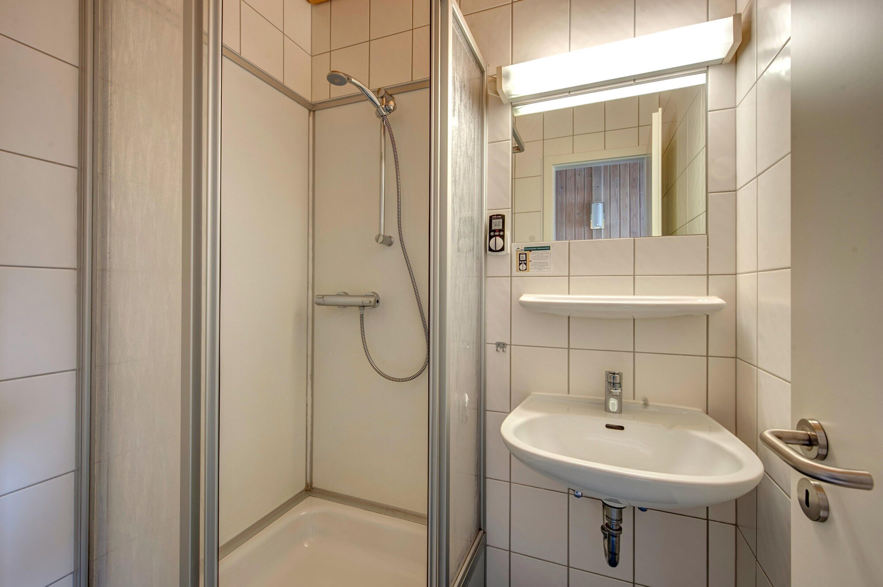 A modern bathroom with a glass-enclosed shower, a white sink, and a mirror above it.
