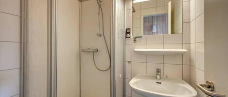 A modern bathroom with a glass-enclosed shower, a white sink, and a mirror above it.
