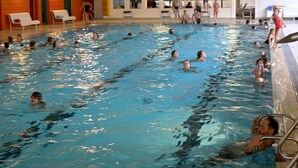 An indoor swimming pool with multiple lanes, a diving board, and a lifeguard chair. - Bungalow im Feriendorf Uslar mit Gartenterrasse (Uslar)