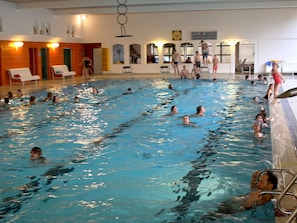 Una piscina interior con varias pistas de natación, un trampolín y una silla para socorrista.
