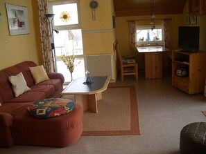 A living room with a sofa, ottoman, coffee table, and a television.