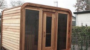 Un cobertizo de madera con dos puertas grandes de vidrio y una ventana pequeña.