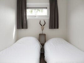 Una camera da letto con due letti singoli, una finestra con tende e una decorazione a forma di teschio di animale appesa al muro.