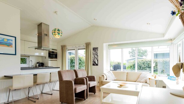 A modern living room with a kitchen area, a sofa set, and a dining table. - Charming Chalet With Dishwasher in Noordwijk (Noordwijk)