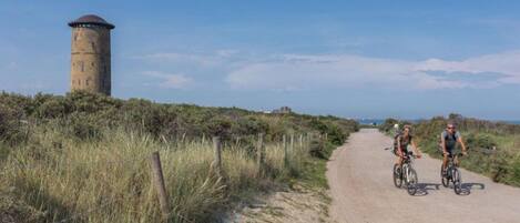 Un sendero de tierra con dos ciclistas, una torre y una valla.