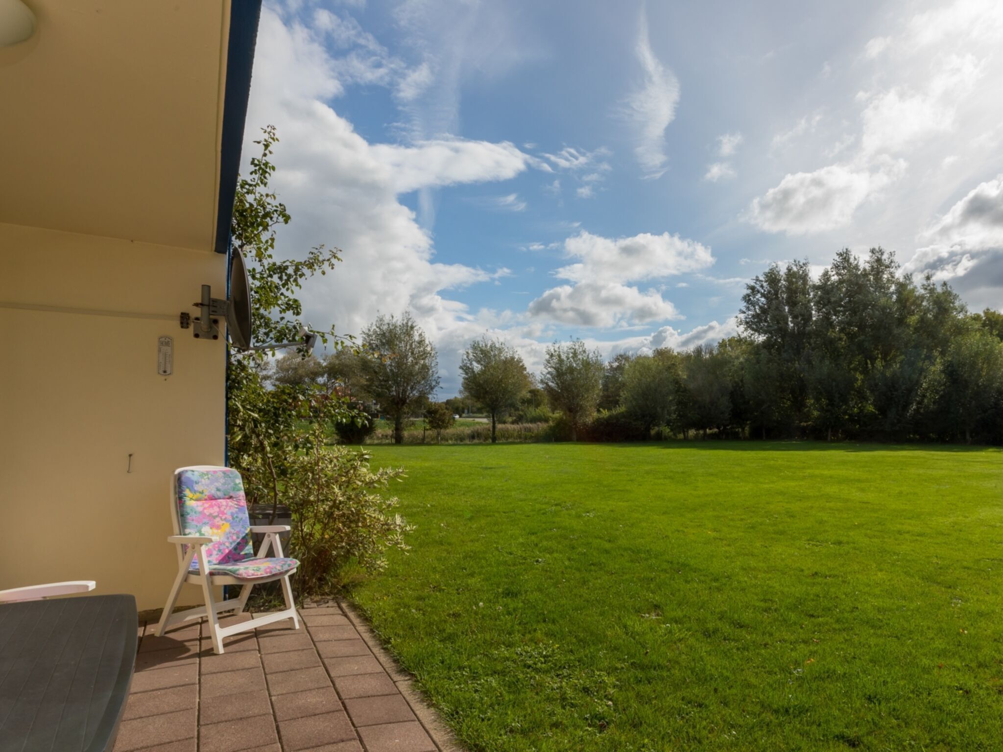 Een terras met gazon, een stoel en een tafel.