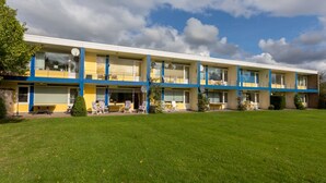 Een motel met twee verdiepingen, een plat dak, meerdere balkons en een verzorgd gazon ervoor.