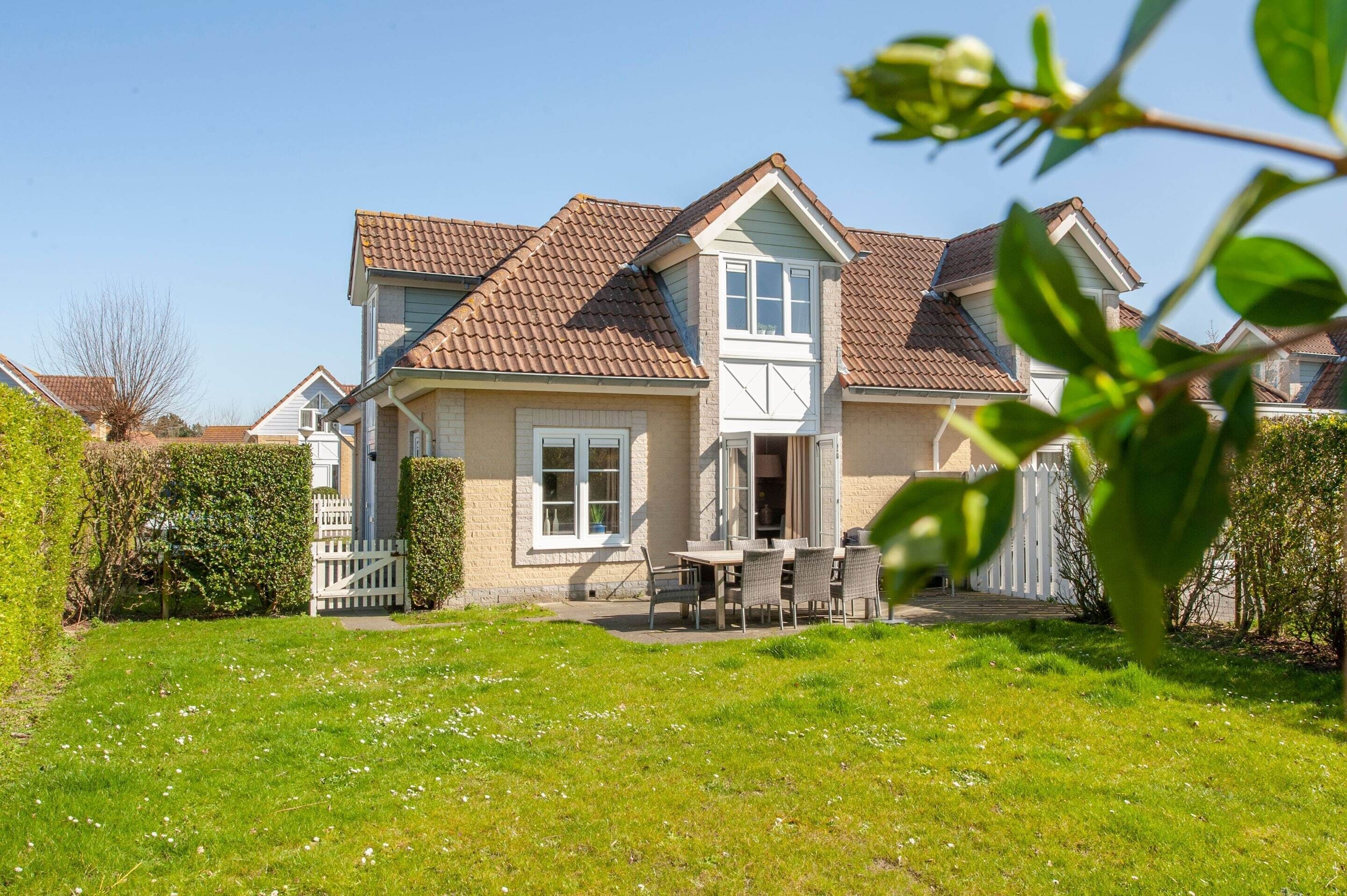 A two-story house with a tiled roof, a front porch, and a well-maintained lawn.