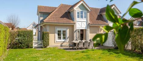 A two-story house with a tiled roof, a front porch, and a well-maintained lawn.