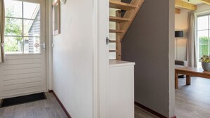 Een trap met houten balken en een witte muur.