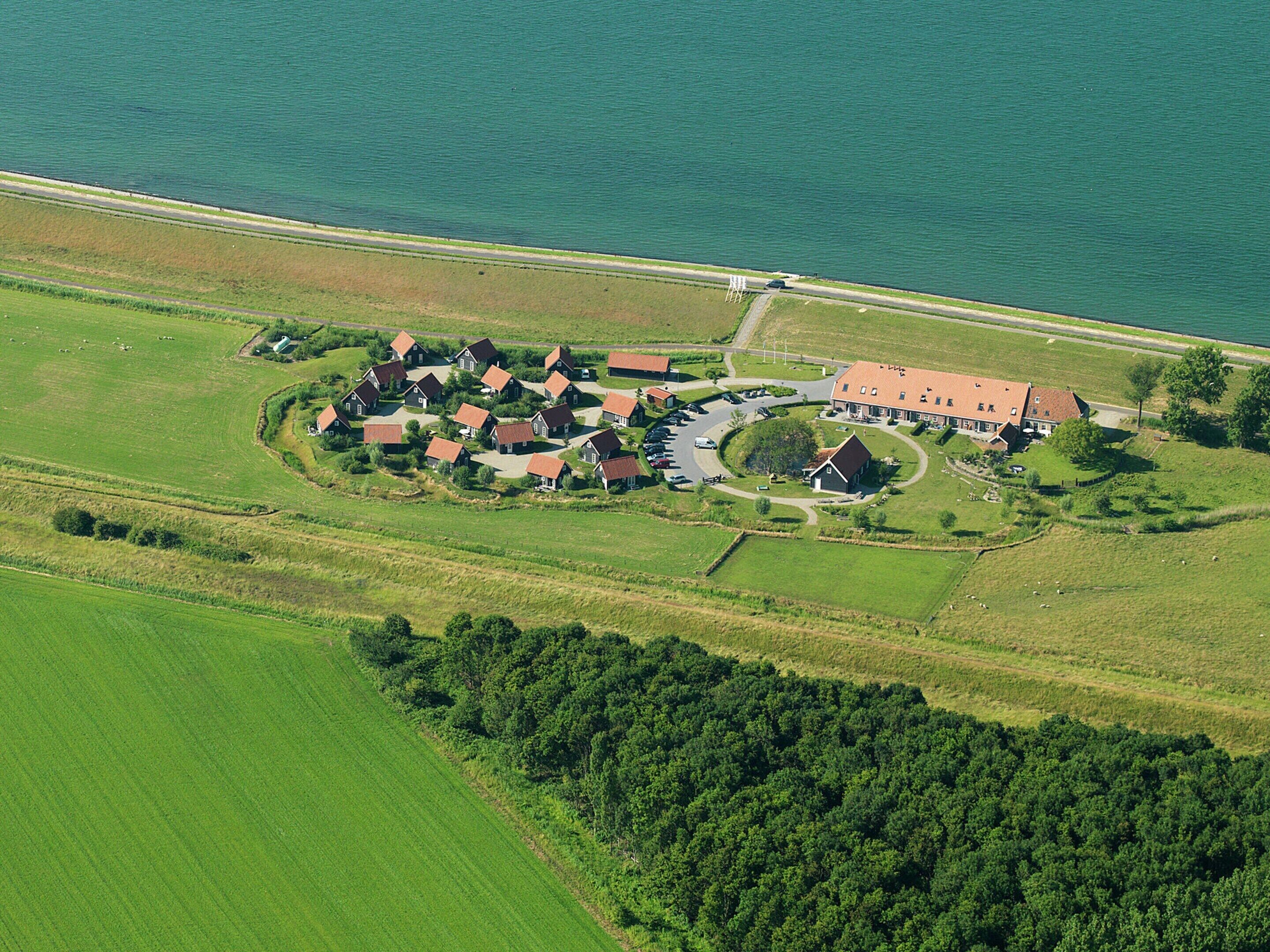 An aerial view of a rural community with houses arranged in a circular pattern around a central building, likely a community center or church, with a road leading to it.