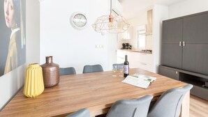 A modern kitchen with a wooden dining table, grey chairs, a large cabinet, and a pendant light. - Stylish Woodland Chalet (Hoge Hexel)