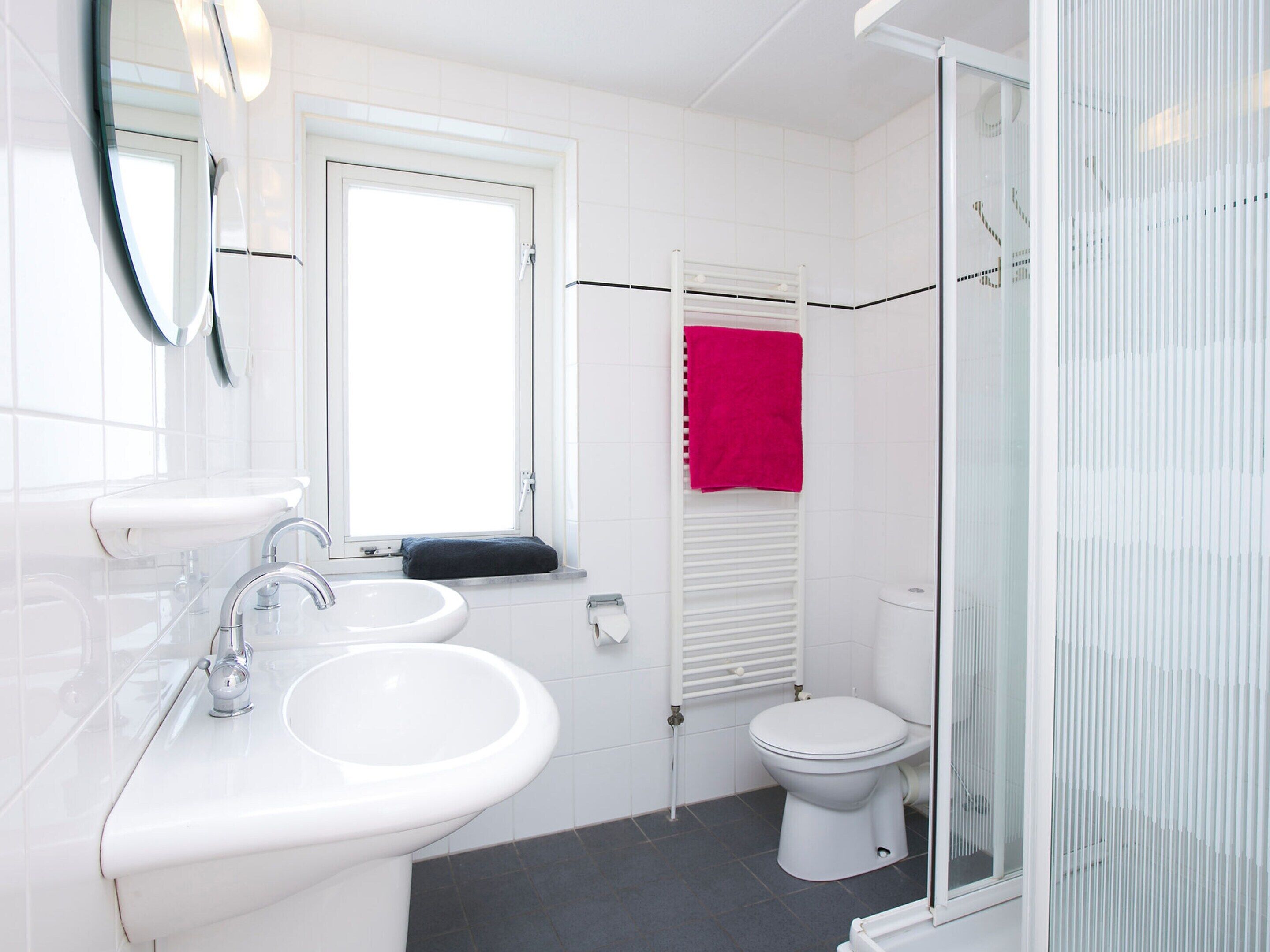 A bathroom with a white sink, mirror, and toilet.