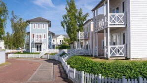 A row of white buildings with balconies and a white picket fence.