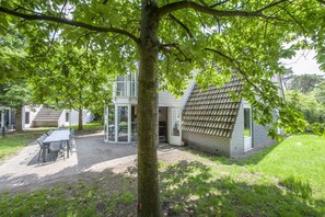 A house with a patio, a dining table, and a tree in the foreground. - Restyled House with 5 Bathrooms near Vrachelse Heide (Oosterhout)