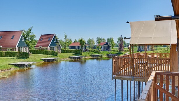 A lakeside view with wooden docks, a covered deck, and houses with red roofs.