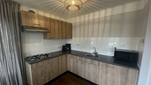A modern kitchen with wooden cabinets, a gas stove, a sink, a coffee maker, and a microwave.