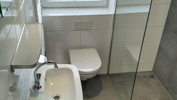 A bathroom with a sink, toilet, and a window.