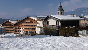 Un pueblo cubierto de nieve con edificios de madera, una iglesia y montañas al fondo.