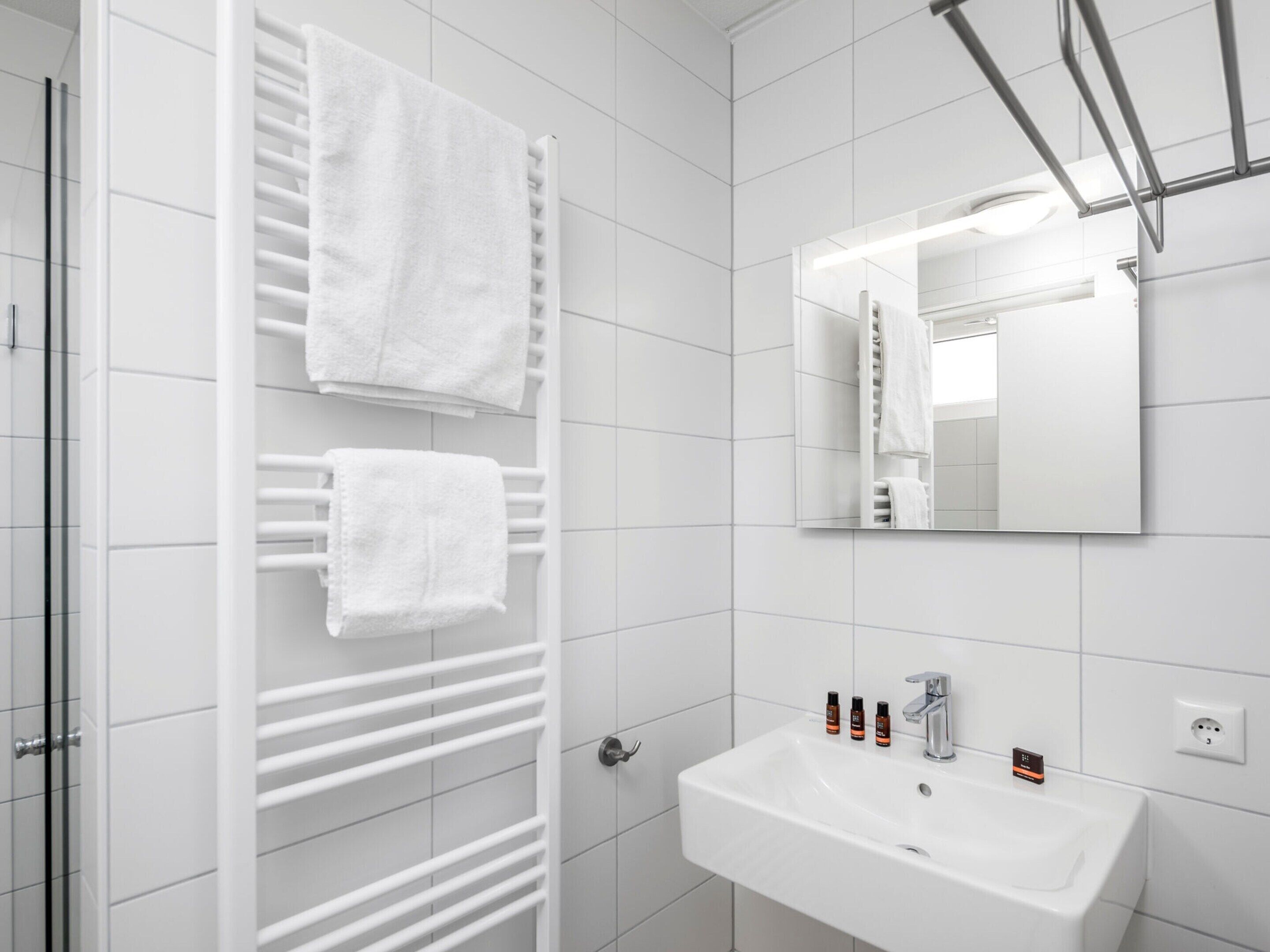 Ein modernes Badezimmer mit Waschbecken, Spiegel und Handtuchhalter.