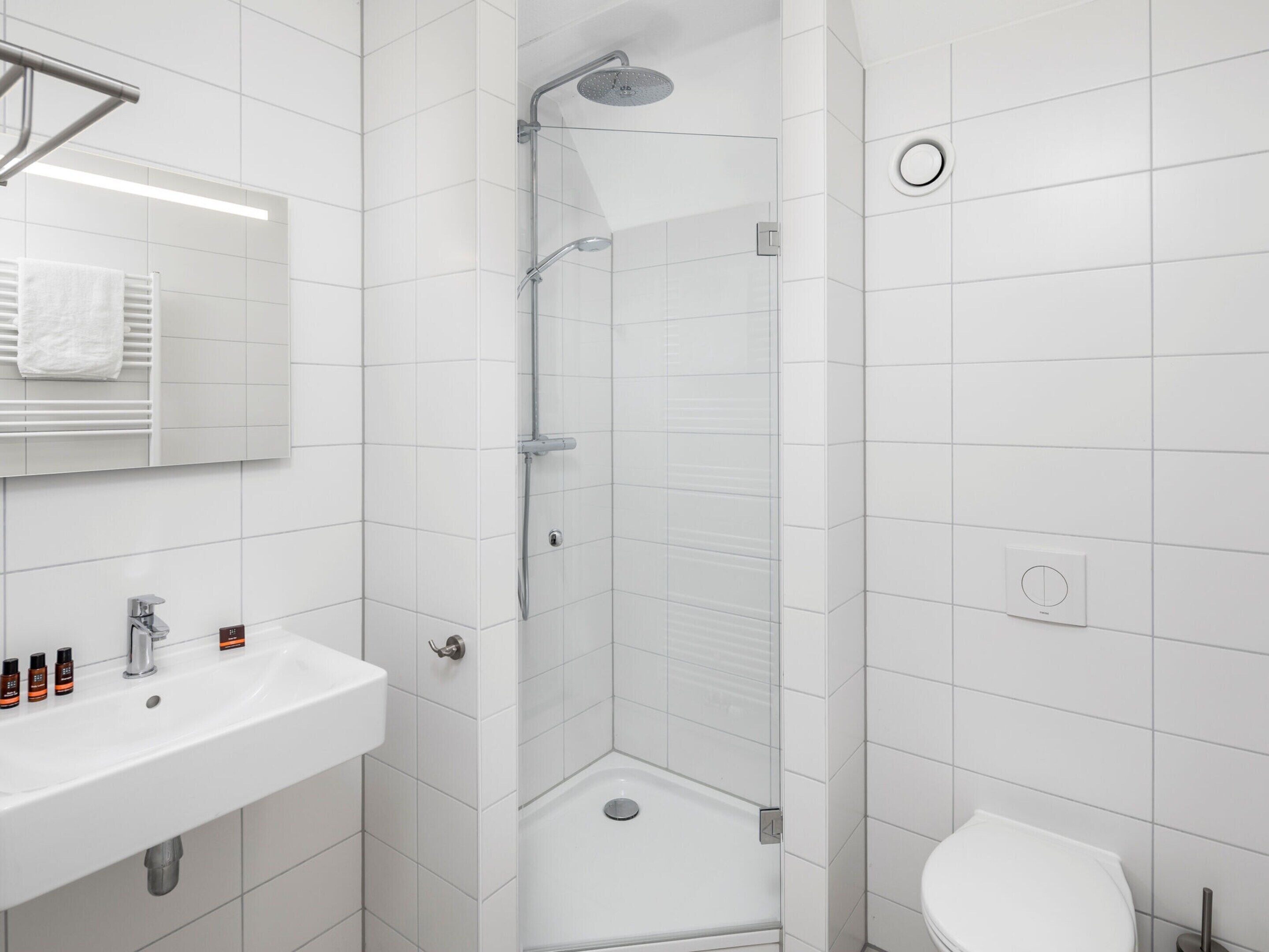 Un bagno moderno con doccia, lavandino e water.