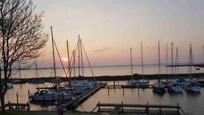 Un puerto deportivo con varios veleros amarrados a muelles de madera al atardecer.
