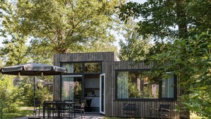 Eine moderne Holz-Blockhütte mit offener Terrasse, Essbereich und Küche.