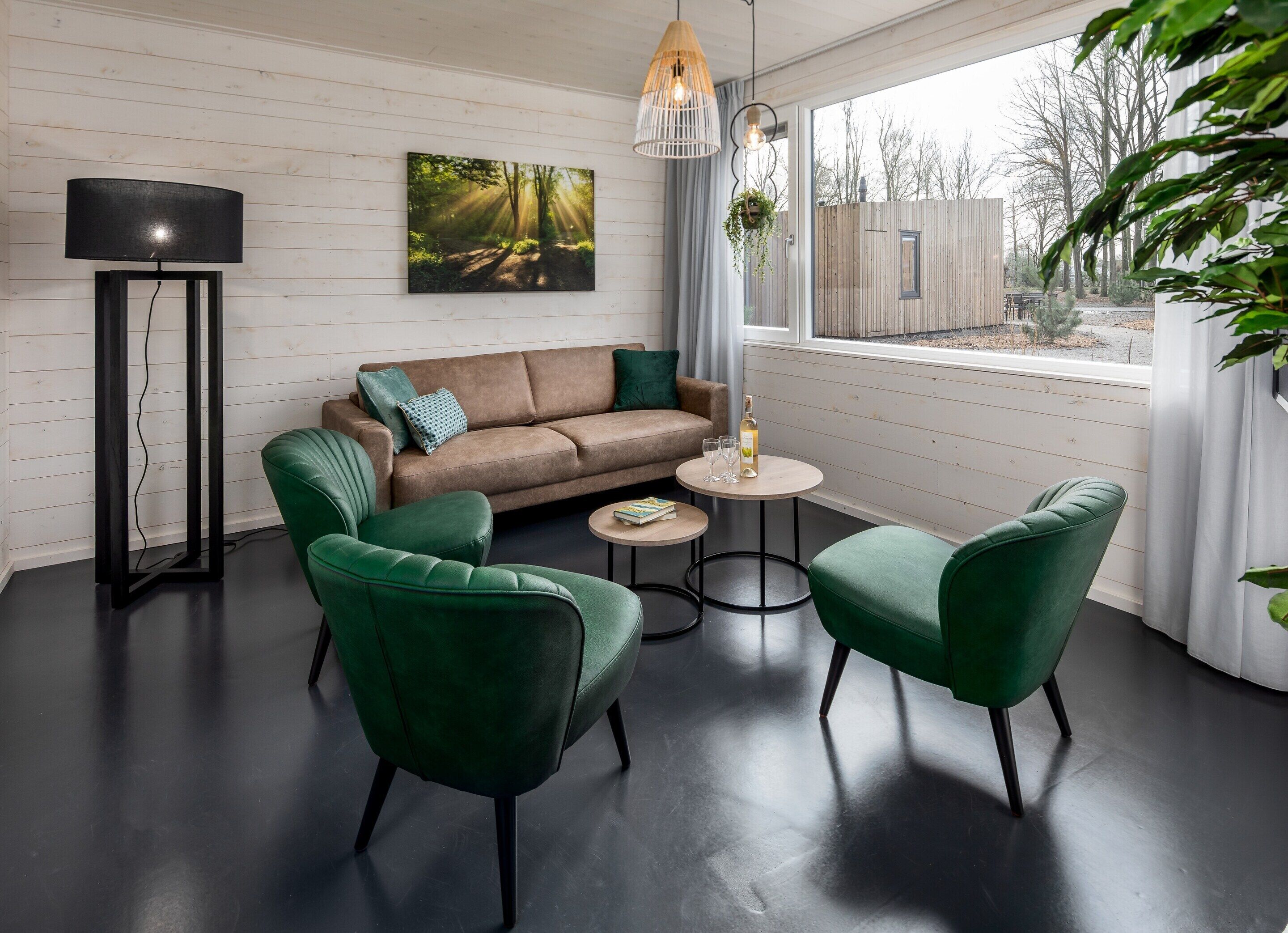 A modern living room with a sofa, two green armchairs, a coffee table, and a floor lamp.