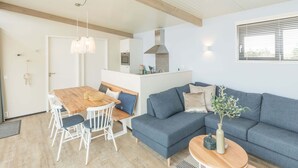 Un salon moderne avec un canapé gris, une table à manger en bois et des chaises blanches.