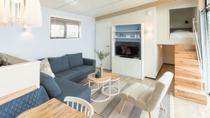 Un espace de vie compact comprenant un canapé, une table basse et un téléviseur fixé au mur.