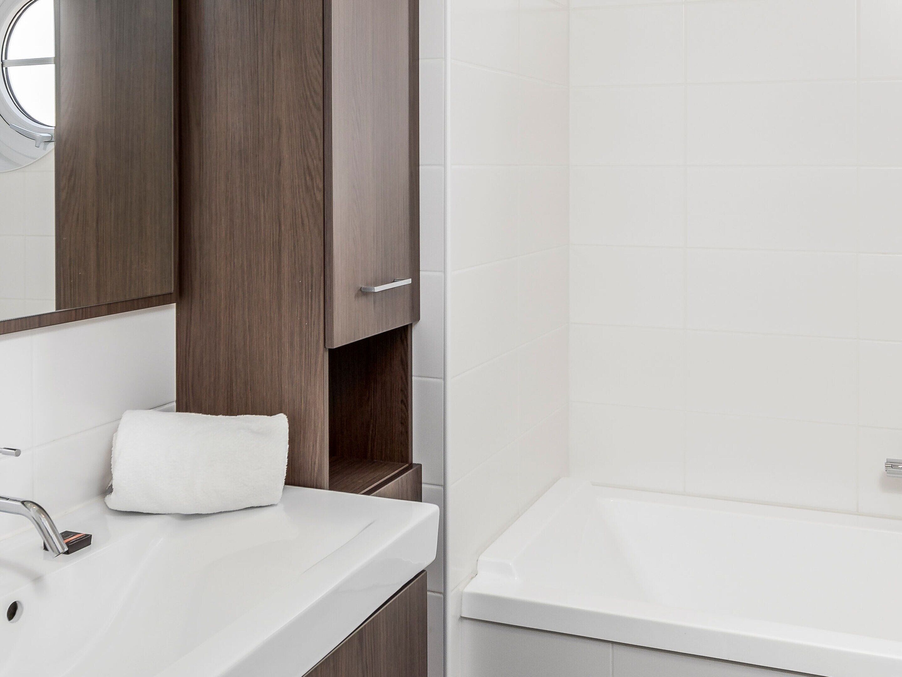 A bathroom with a white sink, a mirror, and a wooden cabinet.