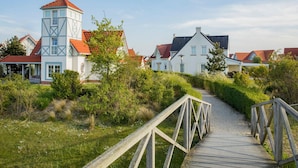 A pathway leading to a row of houses with a prominent tower-like structure.