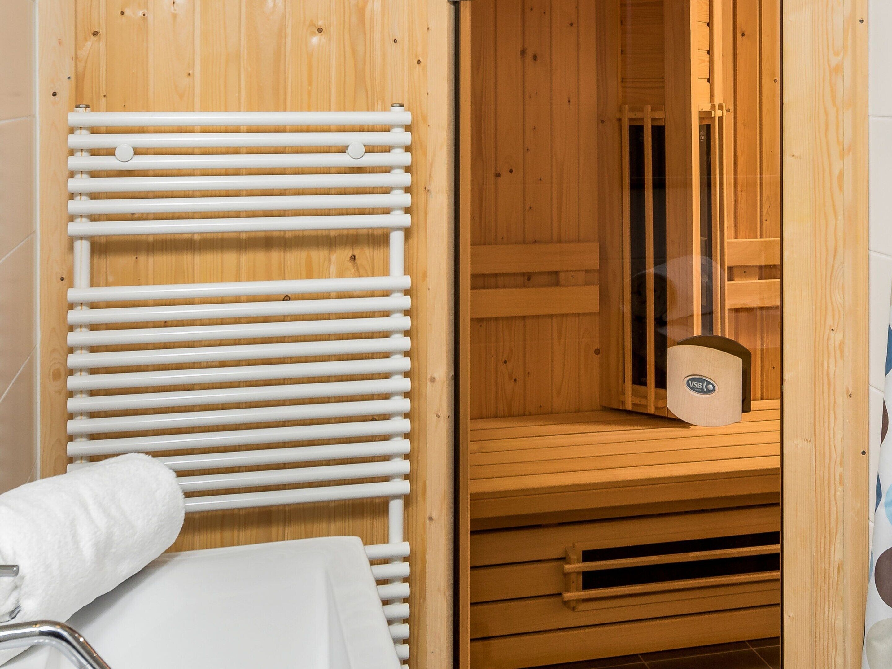 A sauna with wooden walls, a white towel, and a wooden bench.