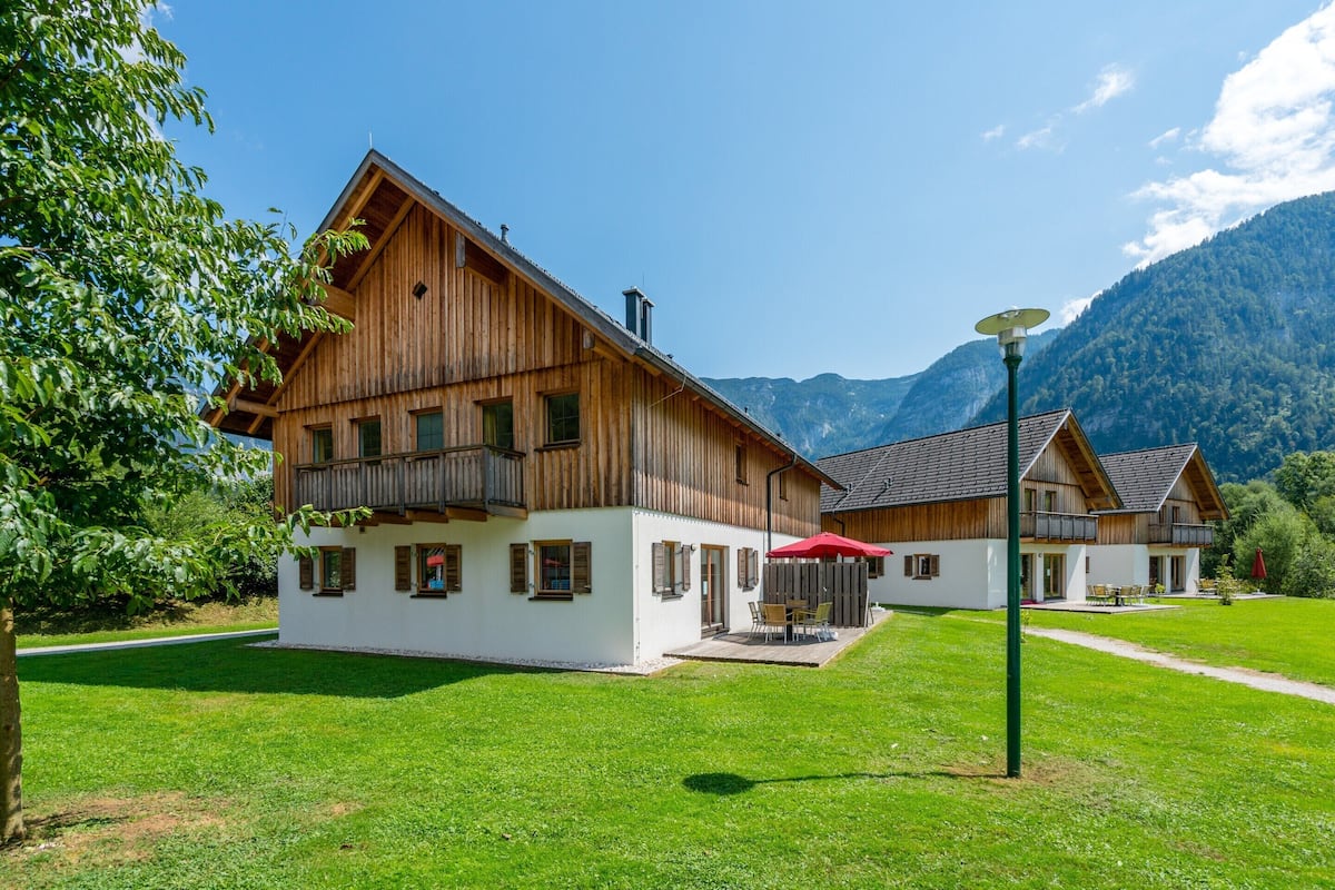 Un chalet en bois doté d’un balcon, d’une terrasse avec mobilier d’extérieur et offrant une vue sur les montagnes.