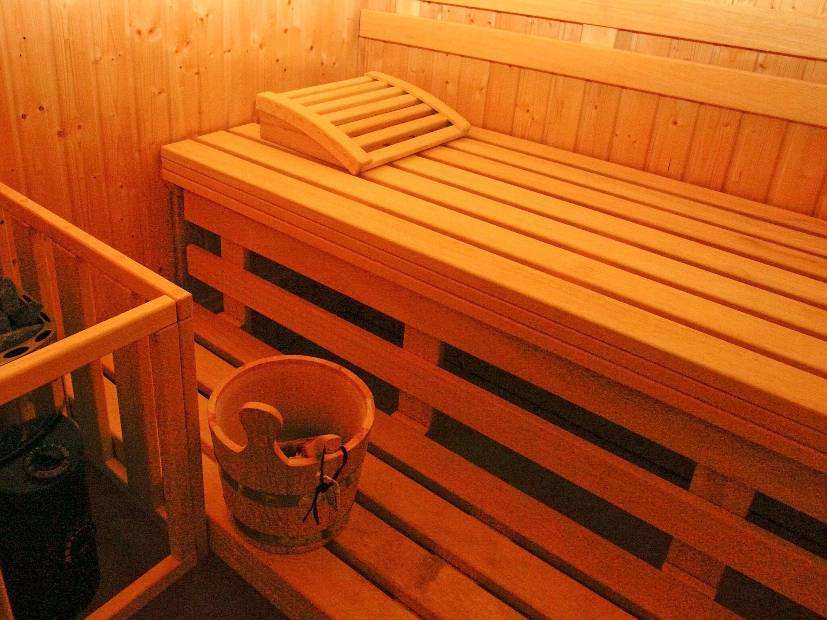 A wooden sauna bench with a slatted seat and a small wooden box on top.