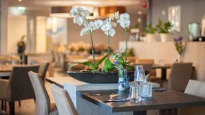 Un moderno comedor con una mesa central decorada con un arreglo floral, rodeado de sillas.
