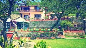 A multi-story building with a balcony, surrounded by lush greenery and a well-maintained garden. - LA CUPOLETTA GILDA- vacation house - lake view Trevignano near Rome (Trevignano Romano)