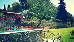 A stone wall with a wooden bridge, a garden with potted plants, and a building with a red roof. - LA CUPOLETTA GILDA- vacation house - lake view Trevignano near Rome (Trevignano Romano)