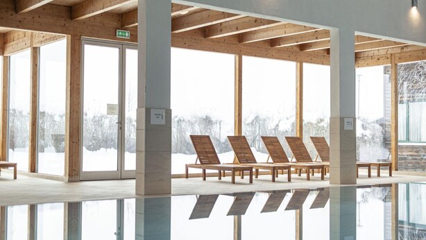 A modern indoor pool area with wooden beams, large windows, and sun loungers. - Spacious Chalet near Ski Area in Sankt Georgen ob Murau (Sankt Georgen am Kreischberg)