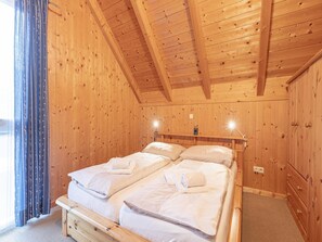A wooden cabin bedroom with two beds, a ceiling light, and a window with curtains. - Spacious Chalet near Ski Area in Sankt Georgen ob Murau (Sankt Georgen am Kreischberg)