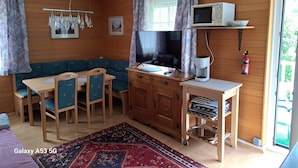 A cozy room with a wooden interior, a television, a desk with a computer, a dining table with chairs, and a patterned rug. - Cozy Apartment in Feld am See near Ski Slopes (Feld am See)