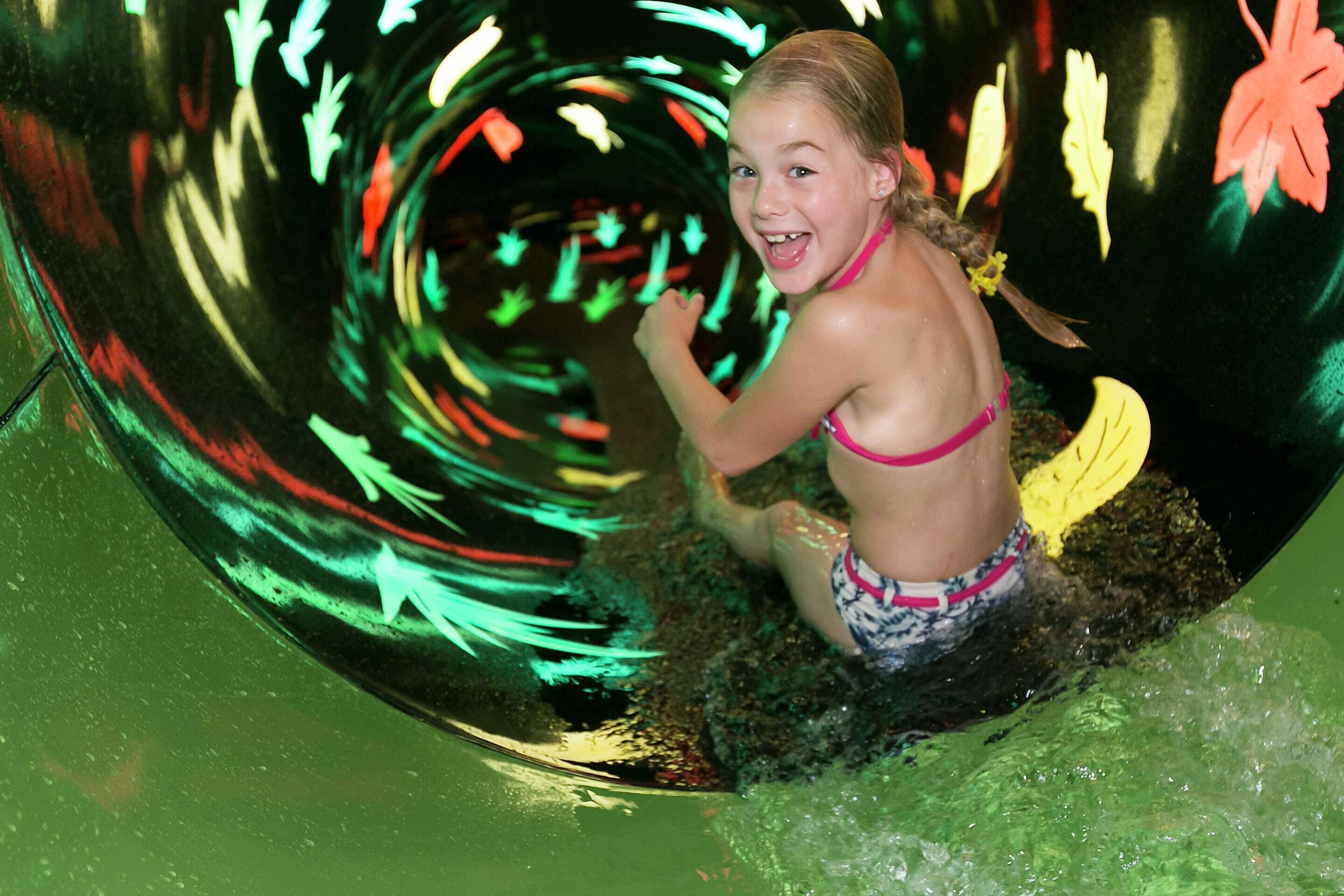 A child in a water slide with a spiral design and leaf-shaped decorations.