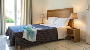 Ein Hotelzimmer mit einem Bett, zwei Nachttischlampen, einem Nachttisch und Blick durch ein Fenster.