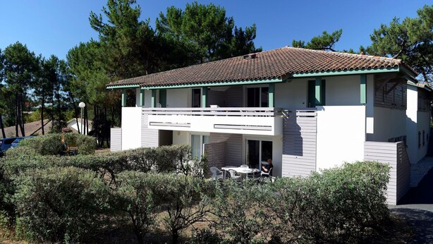 A two-story house with a balcony, surrounded by trees. - Apartment in France With Private Garden (Moliets-et-Maa)