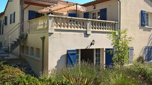 Un bâtiment à deux étages doté d’un balcon, d’un escalier et d’un petit jardin.